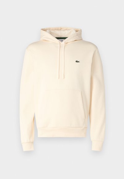 Hoodie couleur crème en tissu doux, doté d'une poche kangourou, de poignets côtelés et d'un petit logo vert sur la poitrine.
