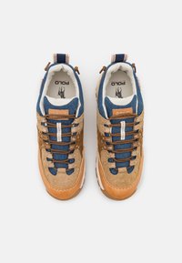 Beige och blå sneakers med överdel i mocka och denim, bruna snören, gummisula och en logotyp-skylt på tungan.