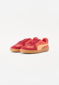 Červené a oranžové tenisky se svrchní částí z semiše a kůže, kulatou špičkou a gumovou podrážkou. Značka PUMA a kontrastní švy.