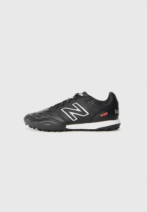 Black athletic shoes with synthetic upper, white accents, textured surface, and a rubber outsole for grip. Features "442" logo in red.