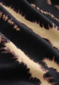 Zwarte stof met beige en bruine tie-dye patronen, met golvende lijnen en een zachte textuur. Het materiaal lijkt lichtgewicht en soepel te zijn.