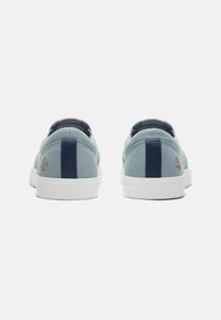 Zapatillas de lona azules con acentos en azul marino y suelas de goma blanca; cuentan con un logotipo en el talón y costuras texturizadas en el lateral.
