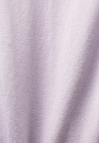 Liliowa dzianina o miękkiej, gładkiej teksturze. Powierzchnia ma jednolity wzór i delikatny blask, co tworzy lekką, przytulną estetykę.