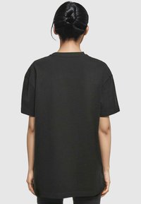 Black cotton oversized t-shirt with short sleeves, round neckline, and no visible patterns or hardware, featuring a straight hem.