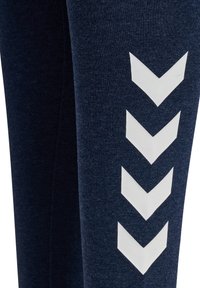 Marineblauer Stoff mit vier nach unten zeigenden weißen Chevronpfeilen, vertikal auf einem Ärmel oder Hosenbein ausgerichtet.