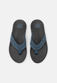 Mørkegrå flip-flops med en blå syntetisk stropp med sømdetaljer. Teksturert fotseng for grep og komfort. Logo på sålen.