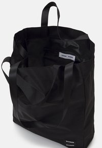 Borsa tote nera in tessuto con doppi manici, ampia internamente e tasca interna con etichetta bianca. Texture liscia, design minimalista.