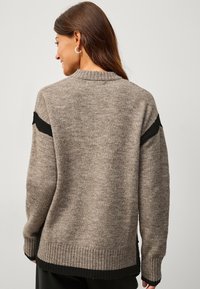 Maglione lavorato a maglia marrone con dettagli neri, orlo e polsini a coste, vestibilità morbida, con scollatura rotonda e tessuto texturizzato.