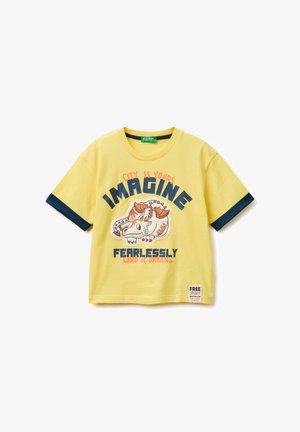 Maglietta gialla a maniche corte con polsini delle maniche blu navy, illustrazione di un drago e testo "La città è tua, Immagina senza paura, Terra urbana."