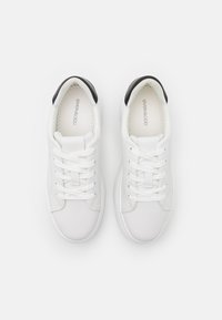 Zapatillas blancas con un acabado suave, puntera redonda y cordones blancos. Acentos negros en el talón, con una suela texturizada y un sutil branding.