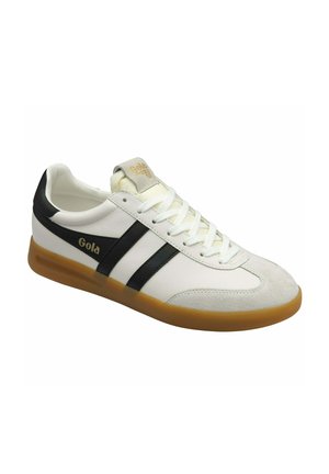 Baskets blanches avec des rayures noires et une semelle en caoutchouc beige. Présentent un embout en daim, des lacets ronds et un logo "Gola" sur le côté et la languette.