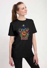 Černé bavlněné tričko s barevným grafickým potiskem "Scooby-Doo", zobrazující postavy na strašidelném pozadí se zelenými akcenty.