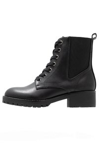 Bottine noire en cuir avec des panneaux latéraux élastiques, bout rond et talon épais. Présente des œillets en métal et des lacets pour un ajustement sécurisé.