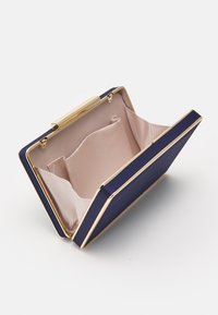 Navy clutch made of smooth fabric with a golden metal frame. Interior features a light tan lining with two compartments.