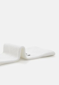 Calcetines blancos con textura acanalada que presentan un diseño doblado. Incluyen un sutil acento de logo negro cerca de la parte superior.