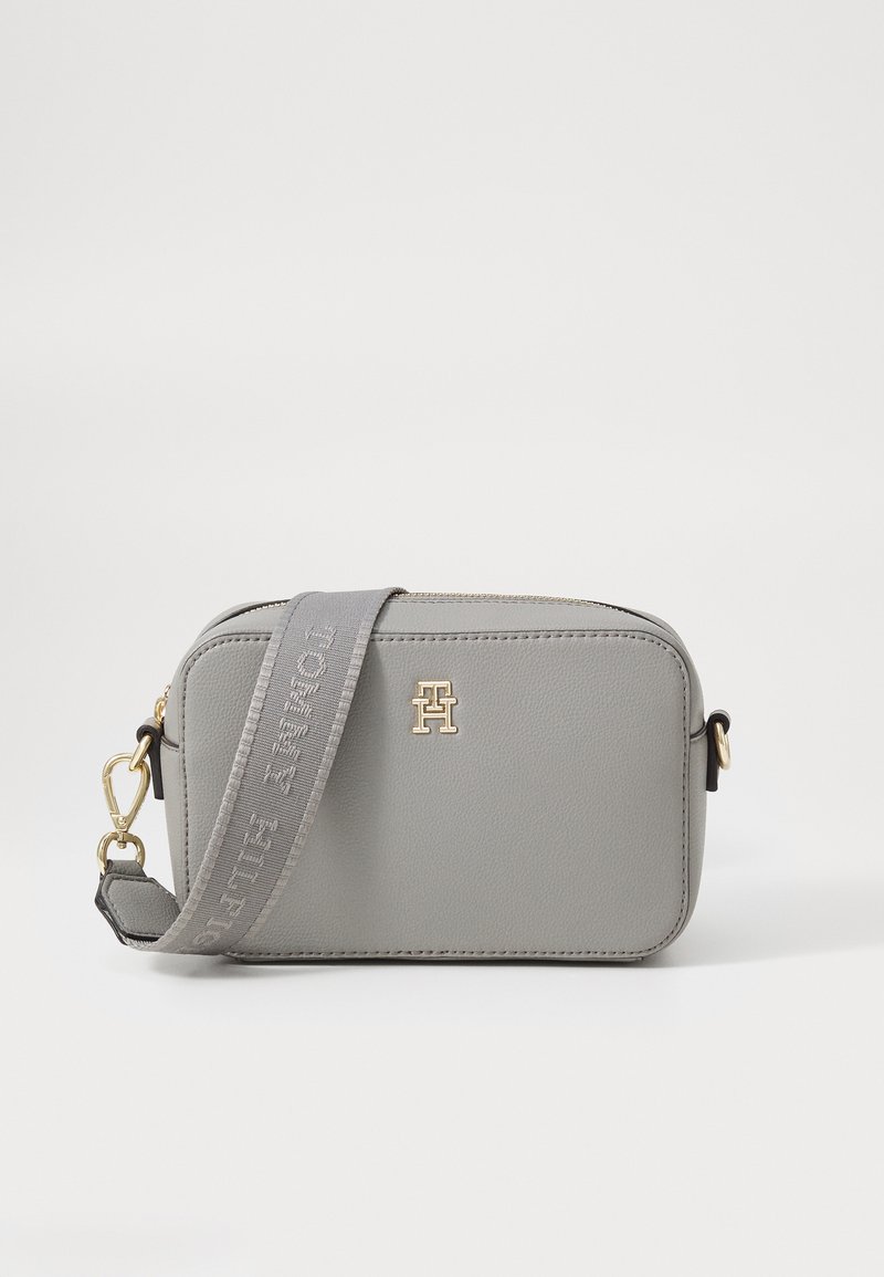 Gray leather crossbody bag with a zipped closure, adjustable strap featuring a logo, and gold hardware accents. Compact rectangular design.
