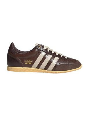 Mørkebrun Adidas Japan sneaker med beige striber, beige snørebånd, perforeret tå og lys tan gummisål, vist fra siden.