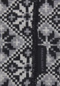 Kari Traa-mönstrad stickad tyg har en svart och grå geometrisk design med en mjuk textur och en svart etikett i kanten.