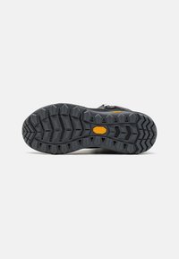 Svart tursko såle med et uttalt mønster, som har dype spor og Vibram-logo, designet for grep på varierte overflater.
