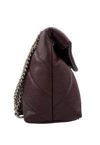 Borsa in pelle bordeaux scuro vista laterale con cuciture a trapunta e tracolla in catena argentata su sfondo bianco.