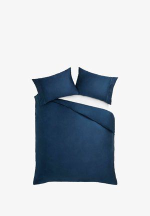 Doppelbett mit dunkelblauem Bettbezug und passenden Kissenbezügen auf weißem Matratzenhintergrund.