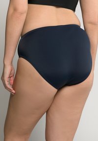 Bikini spodky s vysokým pasem v námořnické modré barvě, vyrobené z hladkého, pružného materiálu. Mají minimální švy a zakřivený design vzadu.