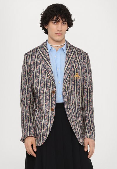 Floral patterned blazer in navy, with vertical stripes and brown buttons, paired with a light blue shirt and black skirt.