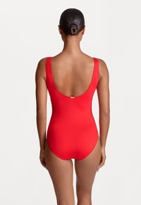 Maillot de bain une pièce rouge avec un dos décolleté, des bretelles larges et une texture lisse. Comprend un petit accent doré près de la couture arrière.