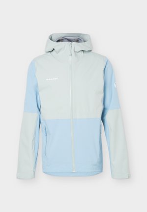Svetlo modra in svetlo siva softshell jakna s kapuco, sprednji zadrgo, stranskimi žepki z zadrgo in logotipom Mammut na prsih in rokavu.