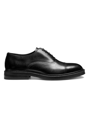 Zapato de vestir Oxford para hombre de cuero negro con cordones cerrados, puntera con costura y tacón apilado, mostrado de perfil sobre fondo blanco.