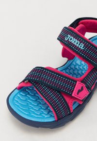 Blå och rosa sandaler med tygremmar som har ett rutmönster, texturerad sula, justerbara remmar och en logotypdetalj.