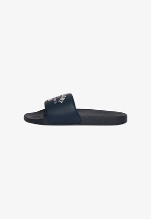 Sandalia tipo slide negra con una amplia tira azul en la parte superior con texto y logo impresos en blanco y rojo.