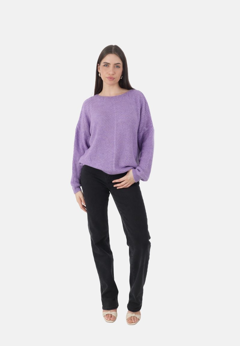 Suéter de punto lavanda con cuello redondo y corte holgado, combinado con pantalones negros y sandalias beige de punta abierta. Textura suave y patrón de punto grueso.
