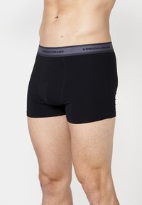 Fekete pamut boxer alsónadrág szürke elasztikus derékkal, amelyen a "KOROSHI BRAND" felirat szerepel. Simább textúrájú, testhezálló kialakítás, közepes hosszúságú fazon.