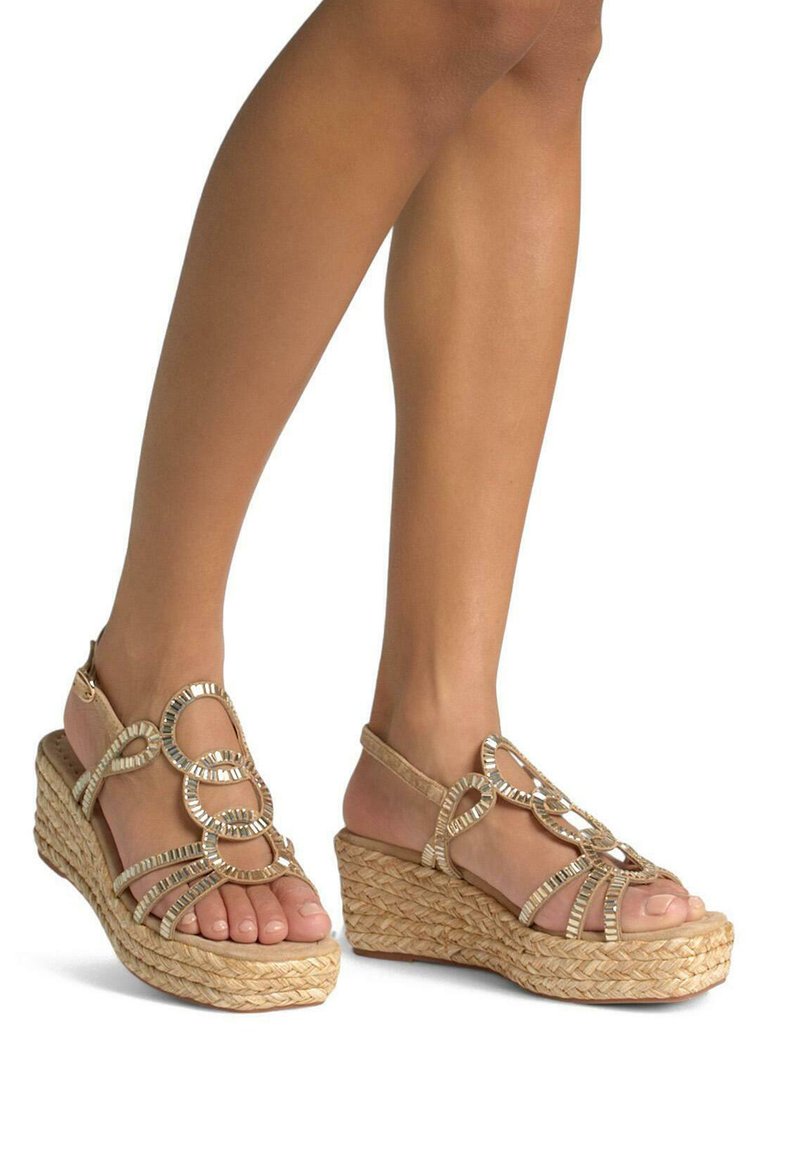 Sandali con zeppa e suola in juta intrecciata naturale. Le cinghie color beige chiaro presentano accenti intrecciati in tonalità dorata, mostrando le dita dei piedi e supporto per la caviglia.