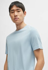 Light blue short-sleeve T-shirt with a textured, waffle-like fabric. Features a round neckline and straight-cut sleeves.