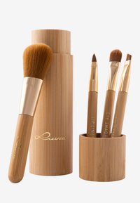 Ein Make-up-Pinselset aus Bambus mit einem großen Pinsel mit weichen Borsten und drei Präzisionspinseln, alle mit goldenen Akzenten und gravierten Etiketten.