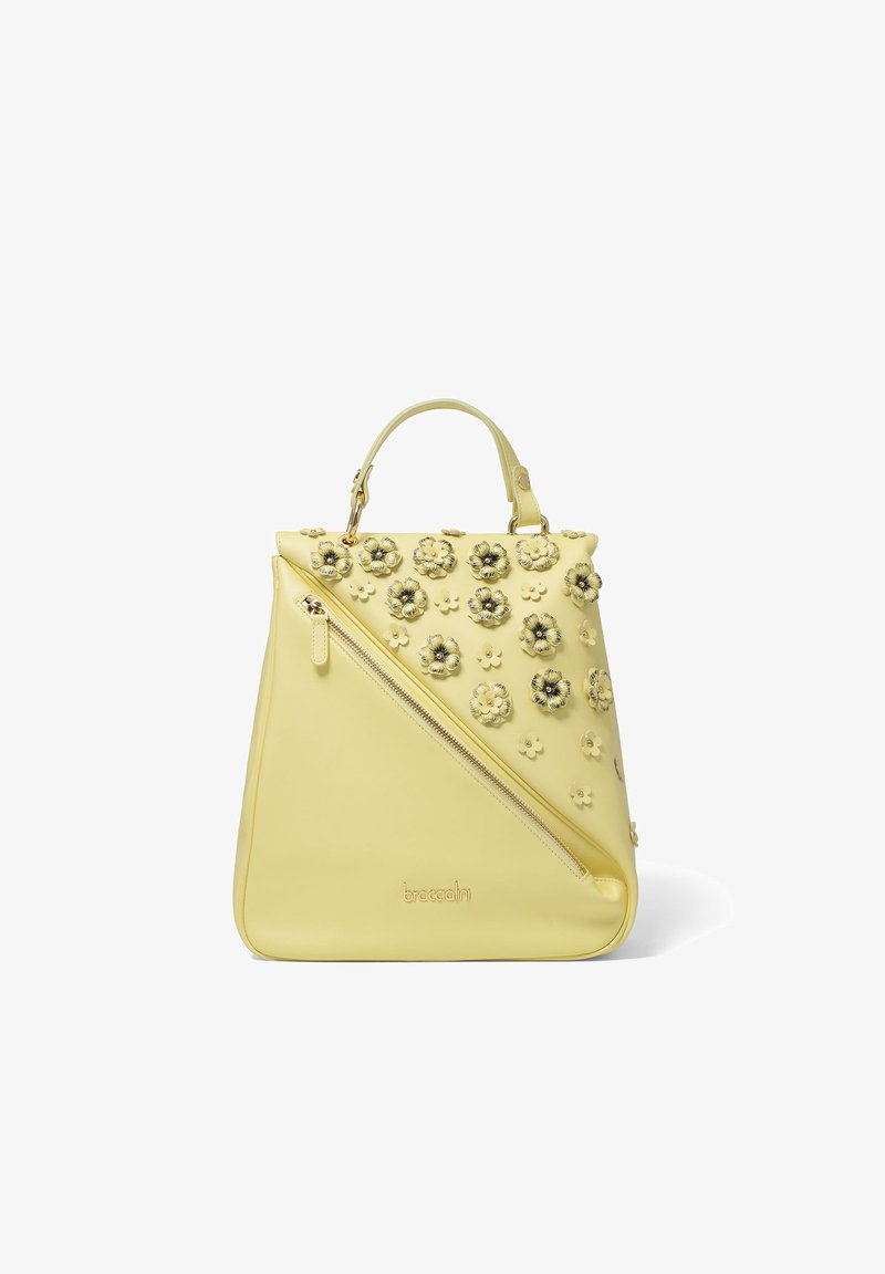 Sac à main jaune avec fermeture éclair diagonale, poignée supérieure et décorations florales 3D sur la partie supérieure, marqué "braccialini" à la base.