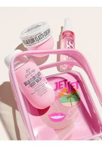Produits de soin de la peau Sol de Janeiro roses, comprenant un gel douche, une crème et une brume, à l'intérieur et à côté d'une trousse de maquillage rose transparente avec un visage stylisé.