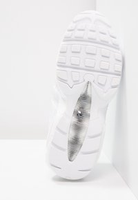 Sole di una scarpa da ginnastica bianca con un design in gomma testurizzata, un compartimento d'aria visibile, linguette piatte per la presa e una finitura liscia.