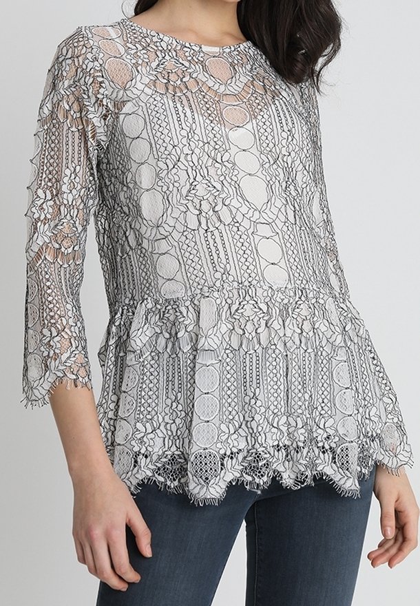 Spetsblus med rund halsringning och trekvartsärmar. Har en lager på lager peplumkant, intrikata blommönster och genomskinlig textur.