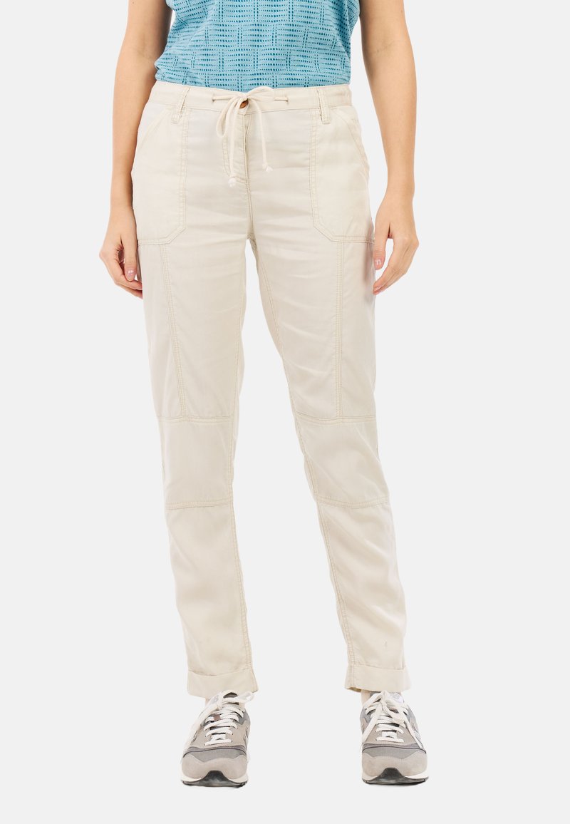Lichtbeige katoenen broek met zakken, een trekkoord in de taille en gestikte details, gedragen met grijze sneakers en een gestructureerde blauwe top.