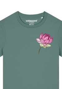 T-shirt à manches courtes de couleur vert sauge, en tissu doux, présentant un design de fleur de lotus rose et vert sur la zone du côté gauche de la poitrine.