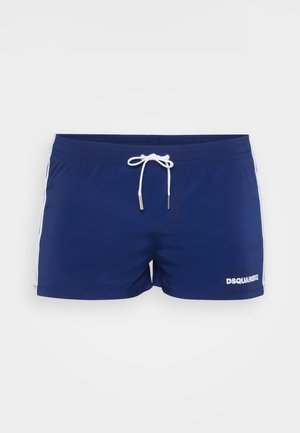 Jūras zila peldbikses ar baltām sānu strīpām un priekšējo sašņorēšanu. Uz apakšējā priekšējā daļa redzama "DSQUARED2" logo baltā krāsā.