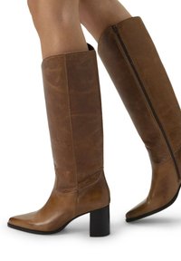 Brown leather knee-high boots with a pointed toe, chunky black heel, and side zipper, featuring a smooth texture and minimalistic design.