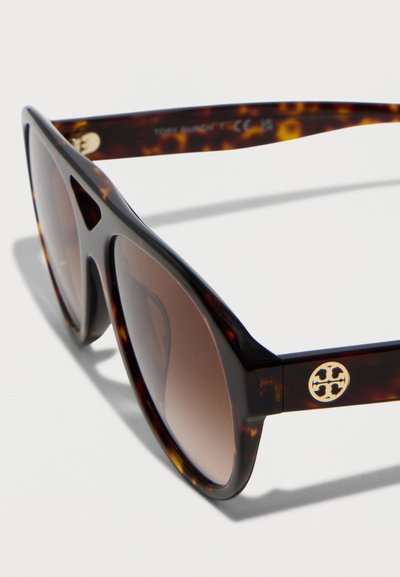 Πολύ μεγάλα γυαλιά ηλίου με σχέδιο χελώνας, καφέ φακούς με διαβάθμιση και χρυσό κυκλικό λογότυπο στο πλάι.