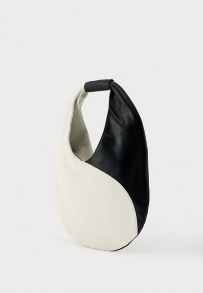 Ασπρόμαυρη τσάντα σε σχήμα ημισελήνου με μια ενισχυμένη λαβή, λεία υφή και μινιμαλιστικό σχεδιασμό σε απλό φόντο.