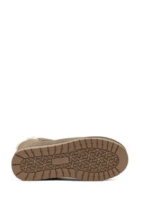 Botte en suède beige avec une semelle en caoutchouc texturé ornée de motifs de flocons de neige. Doublure douce et design à bout rond.