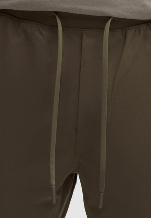 Pantalones deportivos marrones con cintura elástica, que cuentan con cordones ajustables y una textura de tela suave.