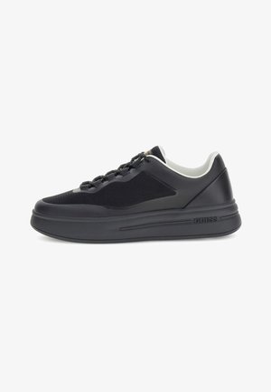 Zwarte low-top sneaker met dikke zool, mesh zijkanten, vetersluiting aan de voorkant, witte interieurafwerking en "GUESS" branding aan de zijkant van de zool.
